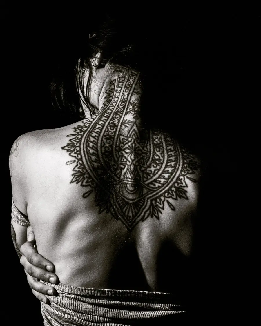Ornamental lace-like blackwork running from the nape to the middle of the back