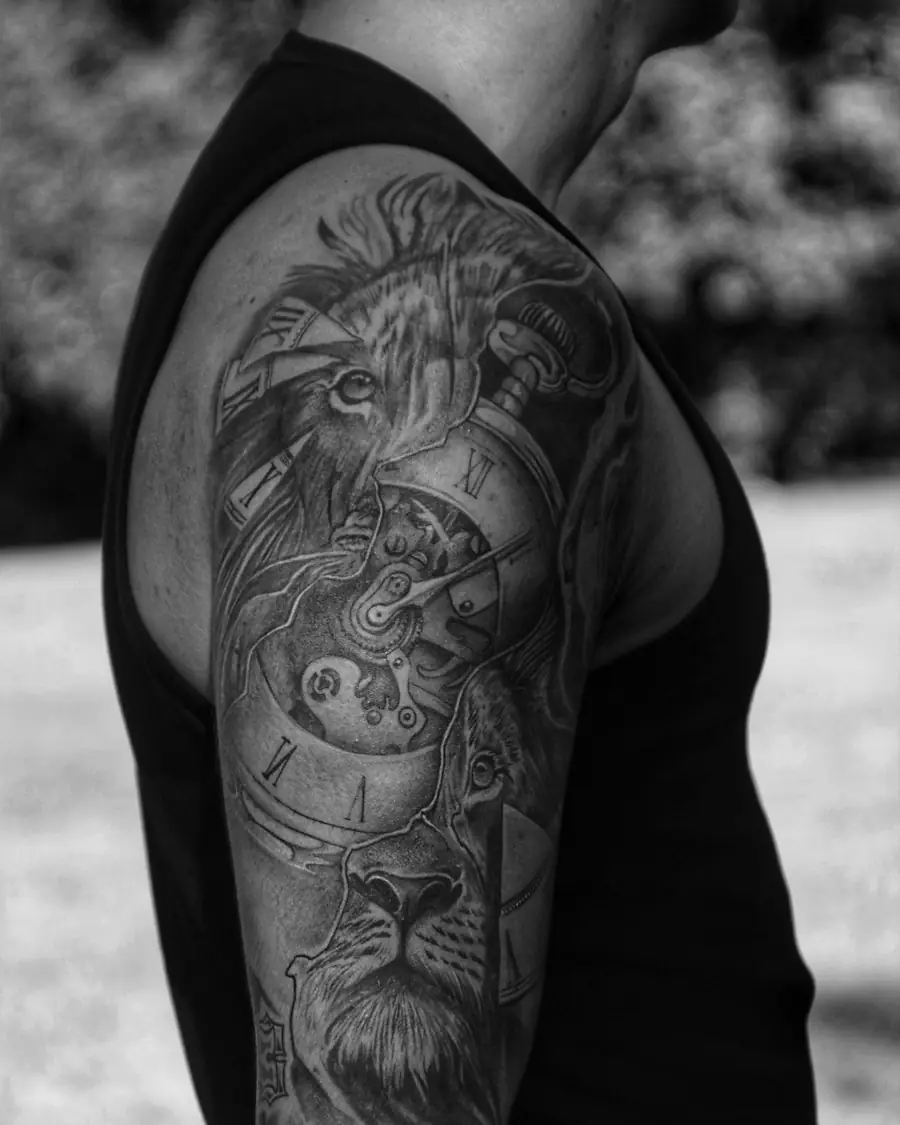 Lion and clock in black and gray realism across the shoulder and upper arm