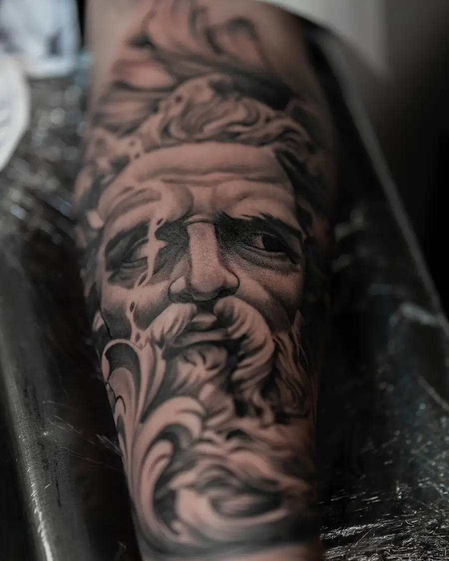Black and gray realism portrait of a bearded man on the forearm